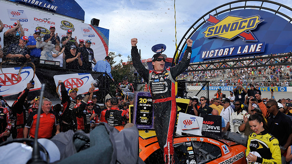 A racer standing on his car being cheered by the crowd